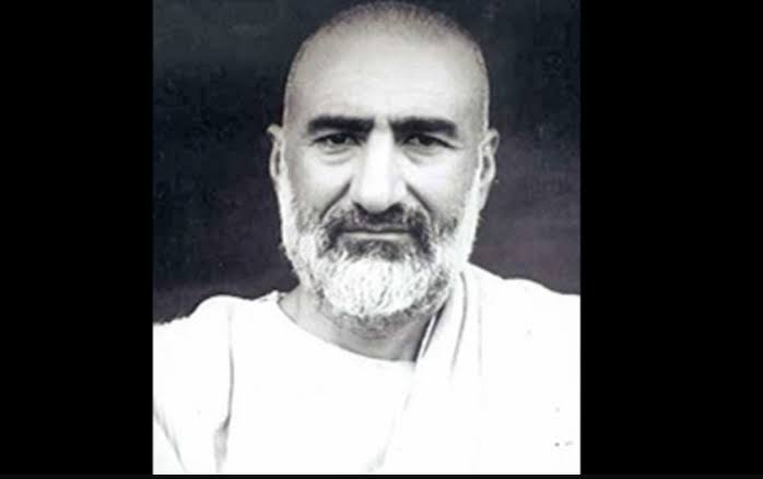 Portrait of Khan Abdul Ghaffar Khan in white homespun clothing against a dark background, facing the camera.